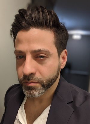 professor in black blazer and white shirt in front of a white and black door